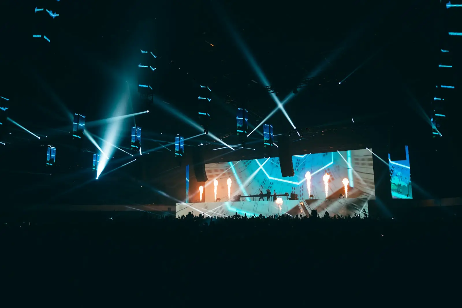 Escenario de concierto con grandes pantallas LED, iluminación y público — imagen referencial