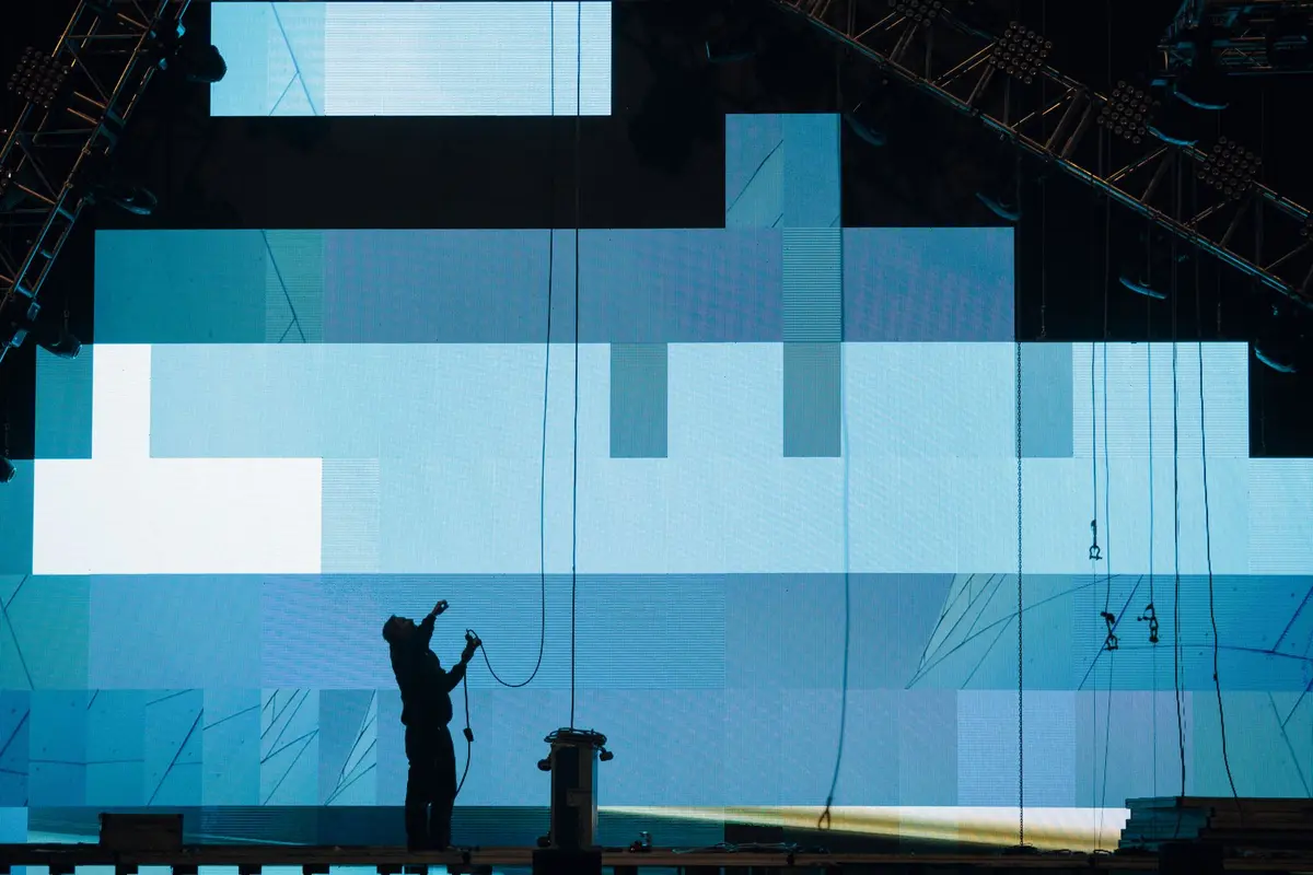 Técnico trabajando con cableado frente a una pantalla LED durante el montaje — imagen referencial